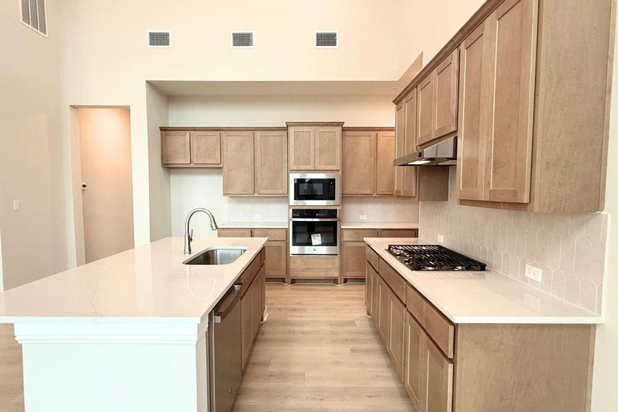 An airy kitchen features an island with a sink, sleek appliances, and light-toned cabinetry. An airy kitchen features an island with a sink, sleek appliances, and light-toned cabinetry.