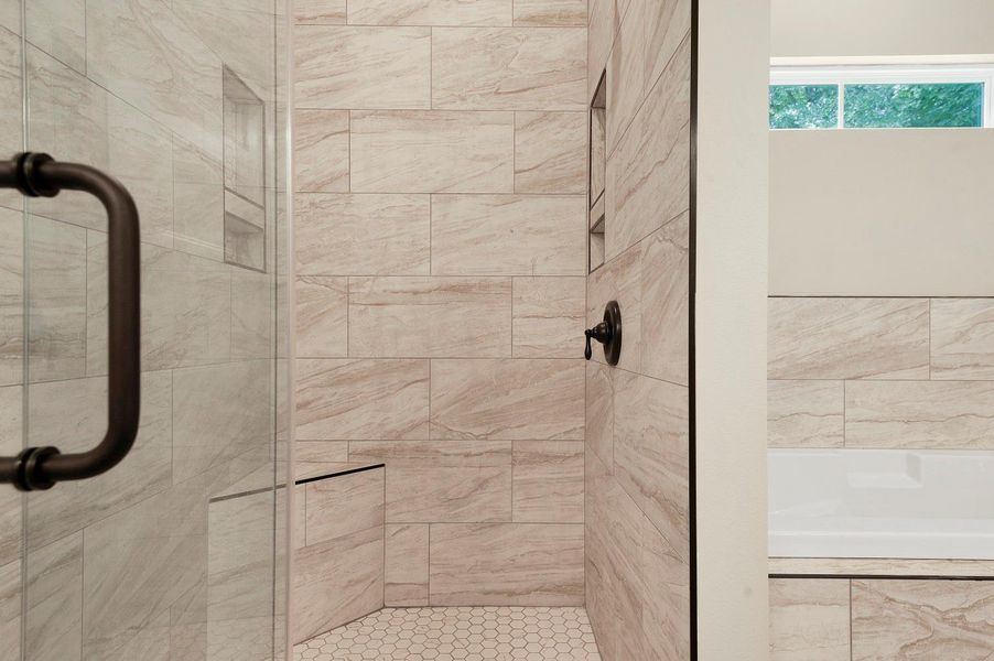 This photo showcases a modern bathroom with a glass-enclosed shower featuring sleek tile walls and hexagonal floor tiles. Adjacent is a bathtub with matching tile surround, offering a clean and contemporary look. This photo showcases a modern bathroom with a glass-enclosed shower featuring sleek tile walls and hexagonal floor tiles. Adjacent is a bathtub with matching tile surround, offering a clean and contemporary look.