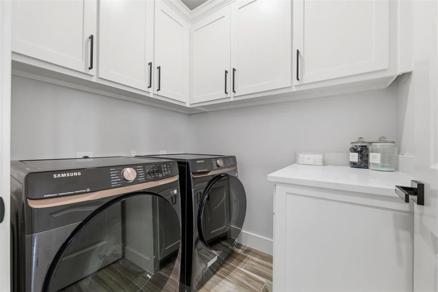 Laundry room featuring cabinet space, separate washer and dryer, and wood tiled floors