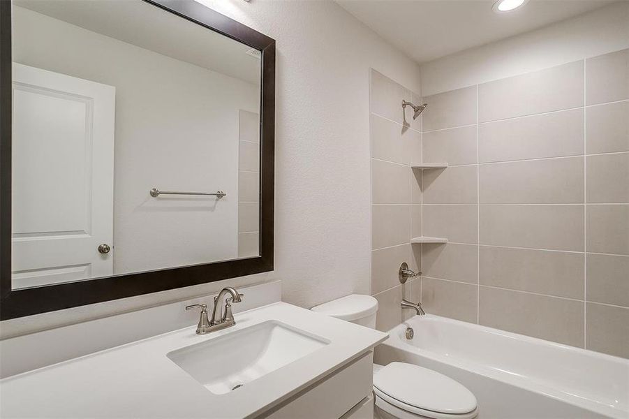 Full bathroom with tiled shower / bath, toilet, and vanity