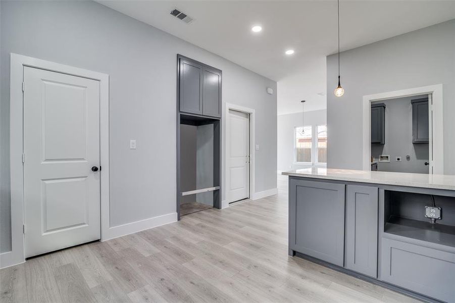 Kitchen with decorative light fixtures, gray cabinets, and light hardwood / wood-style flooring