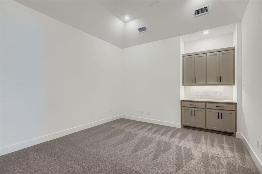 Empty room with dark colored carpet and recessed lighting