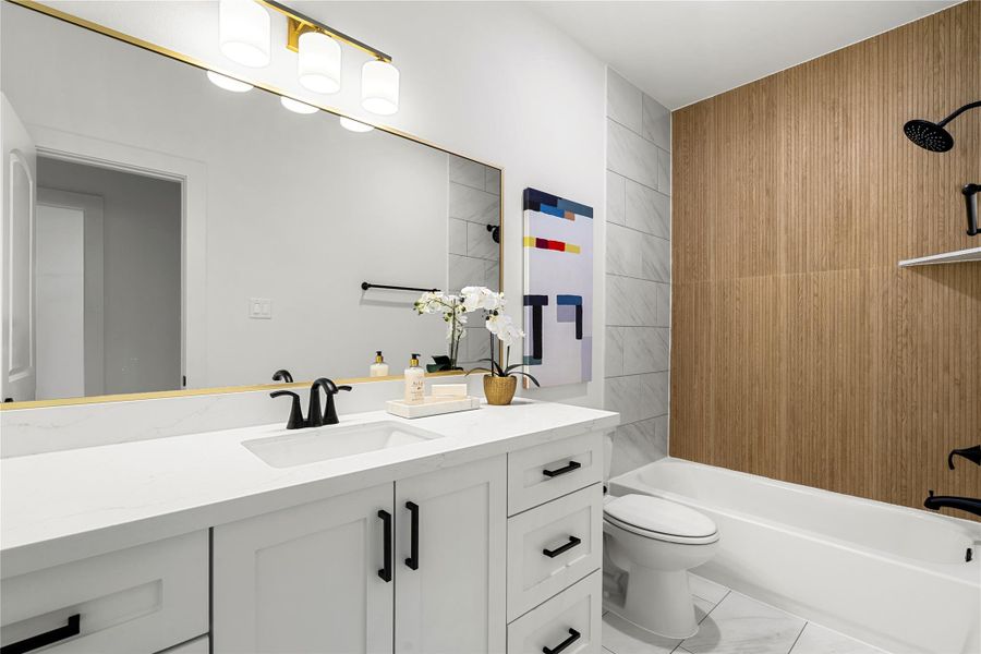 First floor bathroom features a sleek white vanity with black fixtures, a large mirror with stylish lighting, and a bathtub with a wood-accented wall.