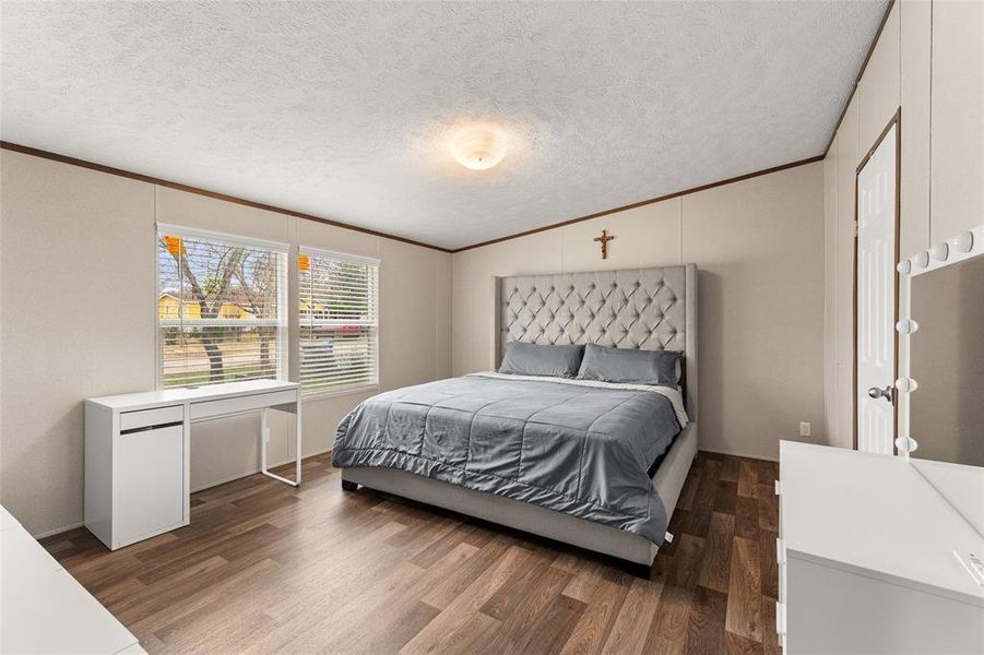 Bedroom featuring crown molding and dark wood-style flooring