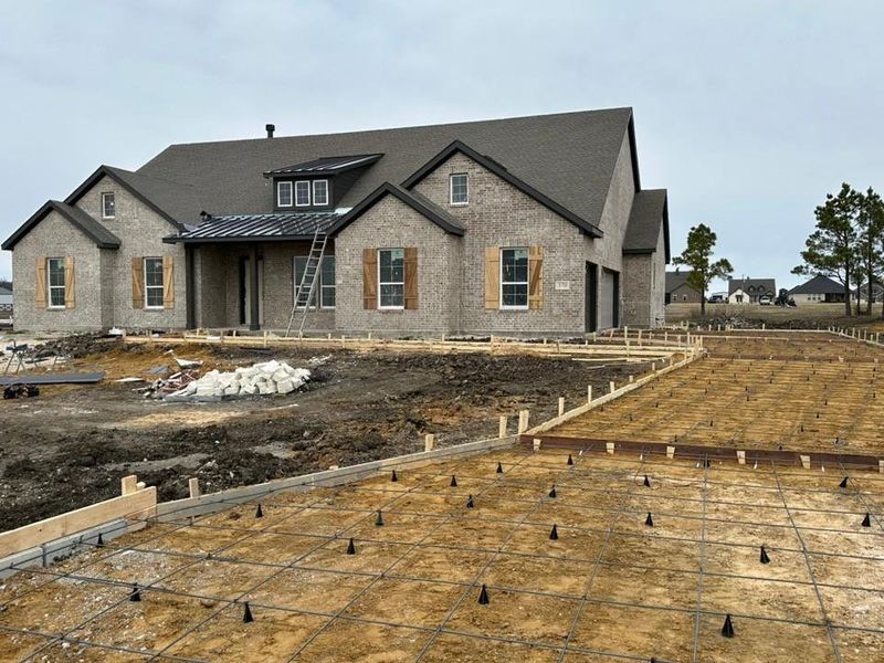 View of front of property with a standing seam roof, a metal roof, and brick siding