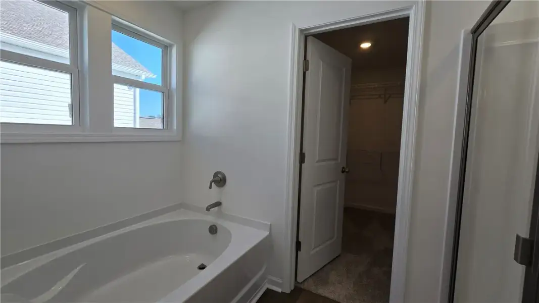 A deep soaking tub sits under double windows besid