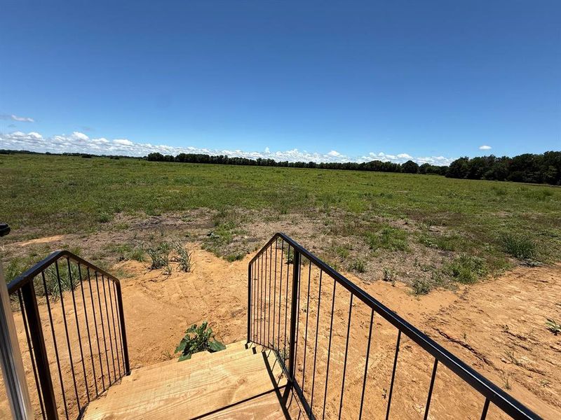 Expansive land parcel featuring natural ground cover, a tree line horizon, and clear sky Expansive land parcel featuring natural ground cover, a tree line horizon, and clear sky