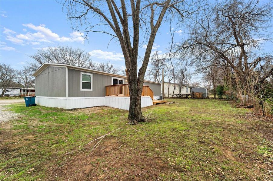 View of side of home featuring a deck and a yard