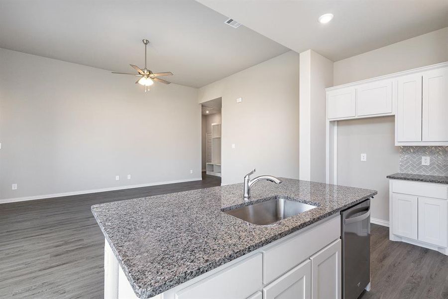 Kitchen with sink, white cabinets, stainless steel dishwasher, and a center island with sink