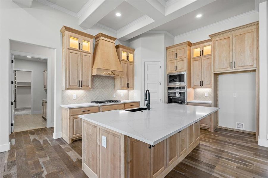 Kitchen with light brown cabinetry, backsplash, coffered ceiling, beam ceiling, and light stone countertops