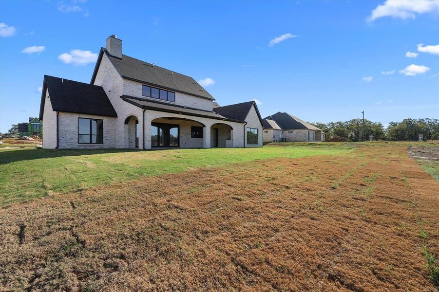 Back of property featuring brick siding, a chimney, a yard, and a patio area
