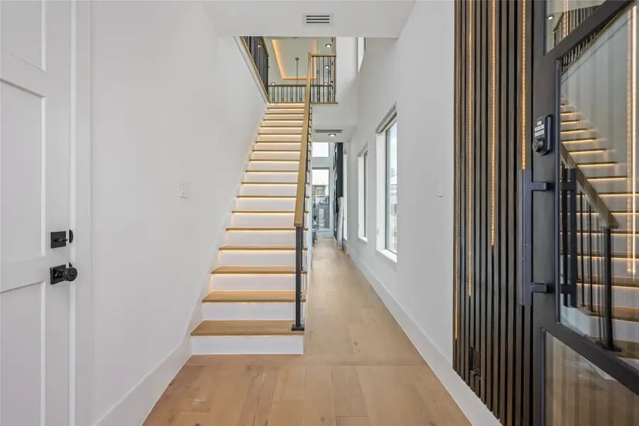 Step into a refined foyer with a custom chandelier, optional LED-accented wall paneling, and rich, engineered white oak flooring that exudes timeless elegance Step into a refined foyer with a custom chandelier, optional LED-accented wall paneling, and rich, engineered white oak flooring that exudes timeless elegance