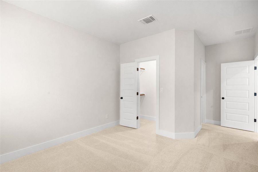 A well-lit bedroom featuring soft carpeting and a convenient walk-in closet. A well-lit bedroom featuring soft carpeting and a convenient walk-in closet.