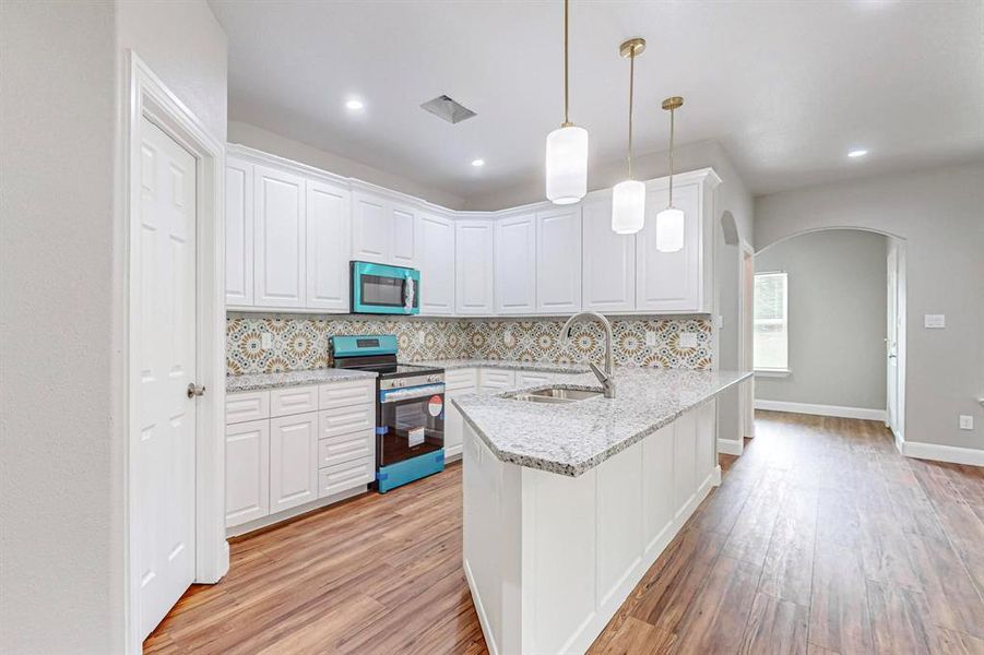 Kitchen featuring kitchen peninsula, appliances with stainless steel finishes, light hardwood / wood-style flooring, backsplash, and sink