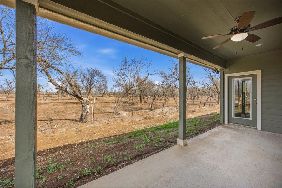 A spacious covered patio overlooks a natural, wooded landscape, offering a tranquil outdoor retreat.