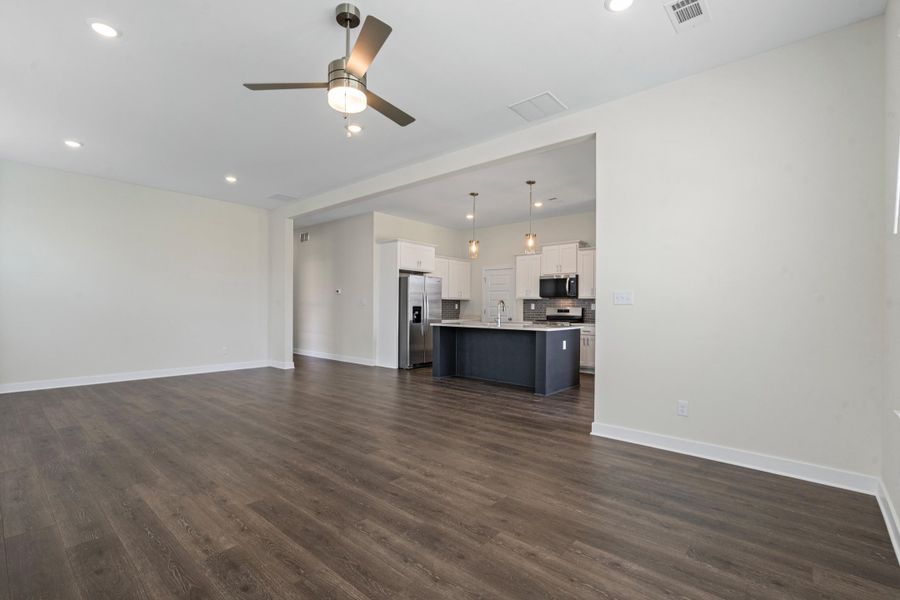 Open-concept living area featuring wood-finish flooring, recessed lighting, and a modern ceiling fan Open-concept living area featuring wood-finish flooring, recessed lighting, and a modern ceiling fan