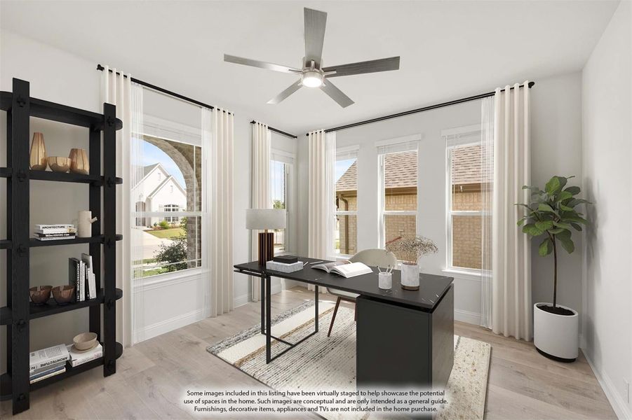 Home office with dark desk, ceiling fan, hardwood floors, and multiple windows with white curtains