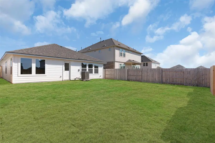 Rear view of house with a fenced backyard and roof with shingles