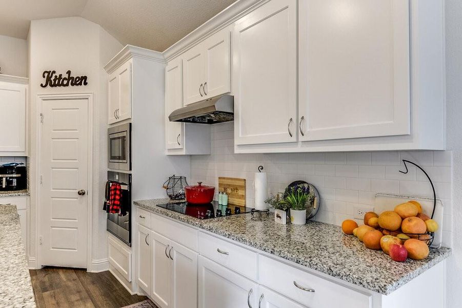 Gorgeous granite countertops complement the white cabinets and backsplash.