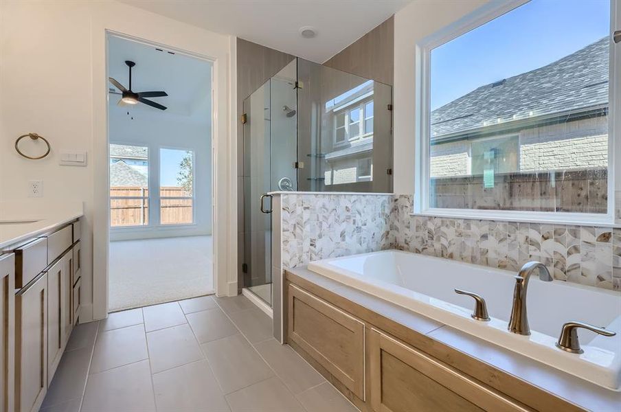 Bathroom featuring vanity, ceiling fan, tile patterned flooring, and plus walk in shower