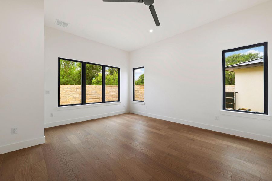 Spacious room featuring wood-finish flooring and multiple black-framed windows
