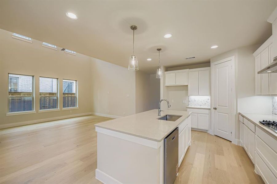 Kitchen with light wood-style floors, tasteful backsplash, recessed lighting, white cabinetry, and an island with sink Kitchen with light wood-style floors, tasteful backsplash, recessed lighting, white cabinetry, and an island with sink
