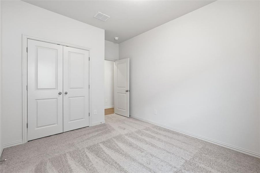Unfurnished bedroom with light colored carpet and a closet