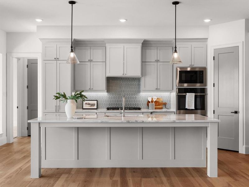 Kitchen with light wood-type flooring, stainless steel appliances, light stone counters, backsplash, and a large island