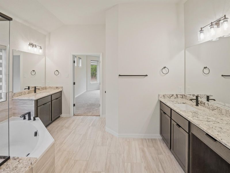 Full bathroom with two vanities, a bath, and lofted ceiling
