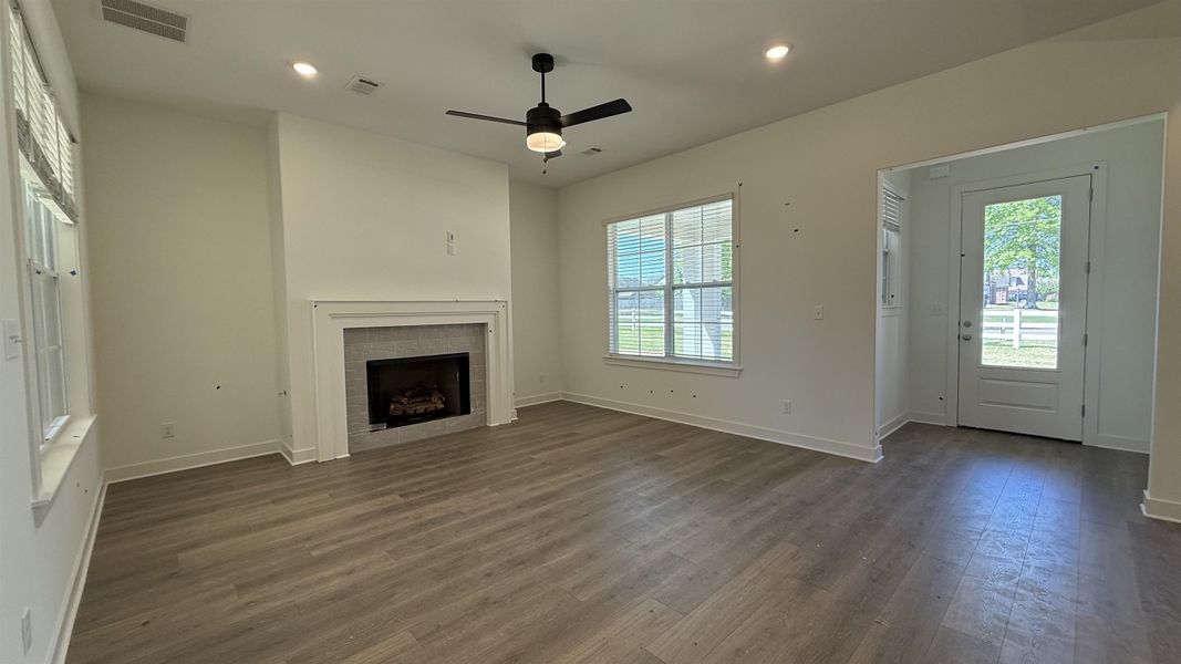 Unfurnished living room featuring ceiling fan, recessed lighting, dark wood finished floors, and a tiled fireplace