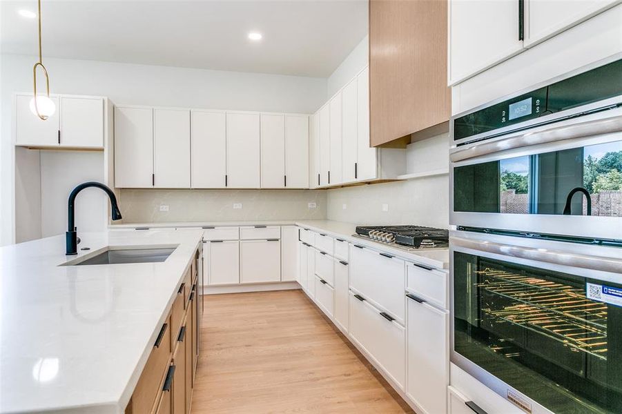 Kitchen featuring appliances with stainless steel finishes, light countertops, recessed lighting, backsplash, and white cabinets Kitchen featuring appliances with stainless steel finishes, light countertops, recessed lighting, backsplash, and white cabinets