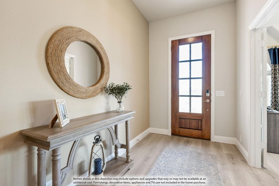 Home entryway with wood front door, glass panels, console table, round woven mirror, and light hardwood floors Home entryway with wood front door, glass panels, console table, round woven mirror, and light hardwood floors