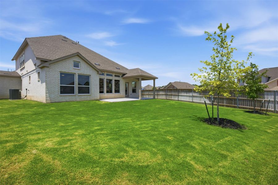 A manicured lawn extends from a covered patio to a private backyard, perfect for outdoor enjoyment.