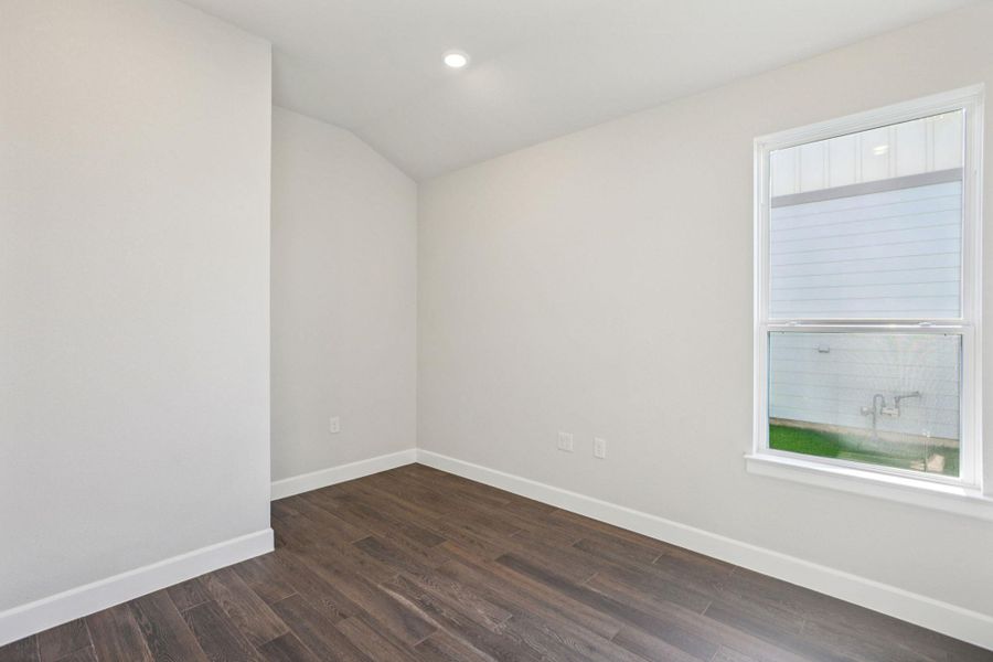Empty room featuring dark wood finished floors, vaulted ceiling, and recessed lighting Empty room featuring dark wood finished floors, vaulted ceiling, and recessed lighting