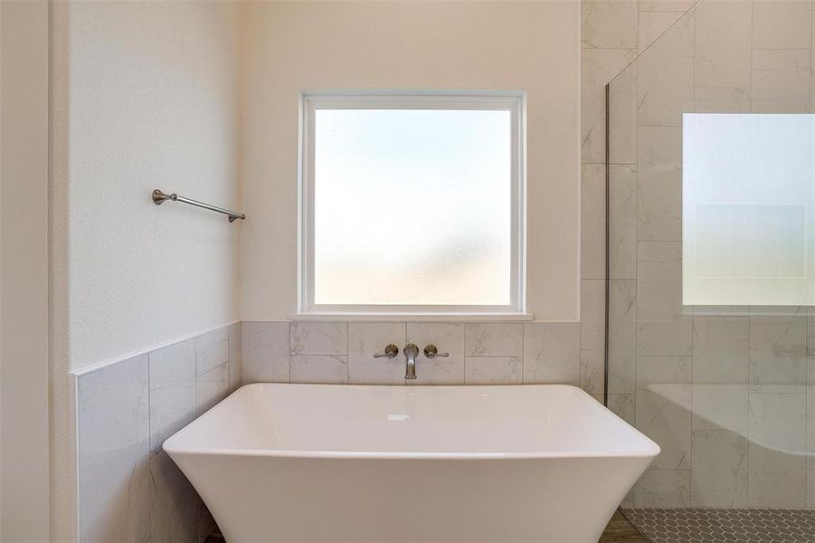 Bathroom featuring tile walls and a bath