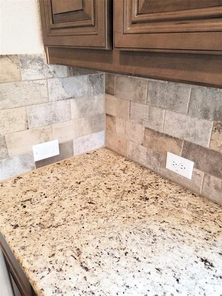 Close up of Giallo Verona granite, tile subway backsplash, and Saddle stained maple cabinets