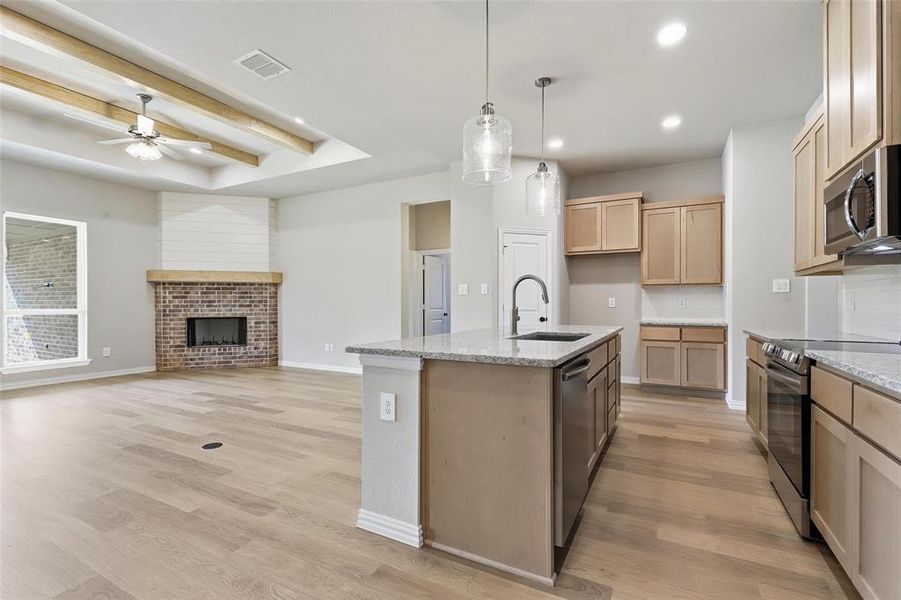 Kitchen featuring light stone countertops, stainless steel appliances, light wood-type flooring, decorative light fixtures, and recessed lighting Kitchen featuring light stone countertops, stainless steel appliances, light wood-type flooring, decorative light fixtures, and recessed lighting
