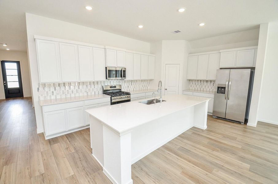 BEAUTIFUL kitchen with LARGE island, soft close cabinets, quartz countertops, gorgeous backsplash, stainless steel appliances and walk in pantry