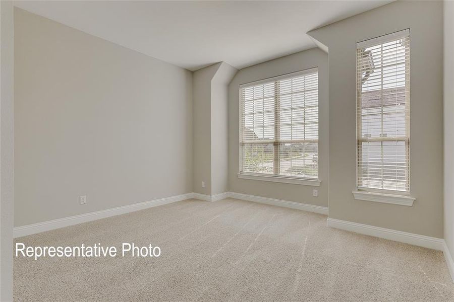 Spacious interior room featuring light-colored carpeting, neutral painted walls, and white baseboards