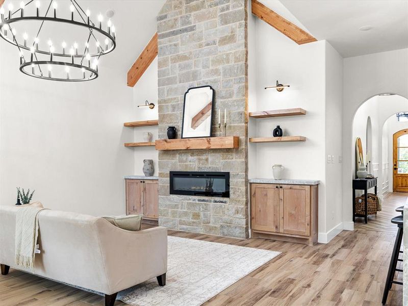 Living room featuring arched walkways, a fireplace, lofted ceiling, and light wood-type flooring