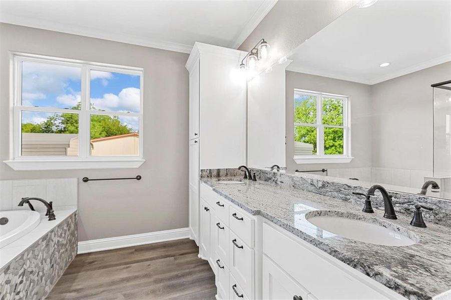 Bathroom featuring vanity, tiled tub, crown molding, and wood-type flooring