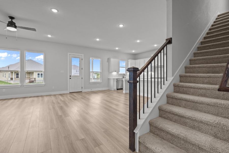 A large room with a wood floor and a wood staircase. A large room with a wood floor and a wood staircase.
