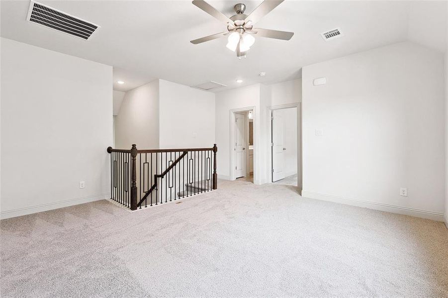 Carpeted spare room featuring ceiling fan and vaulted ceiling