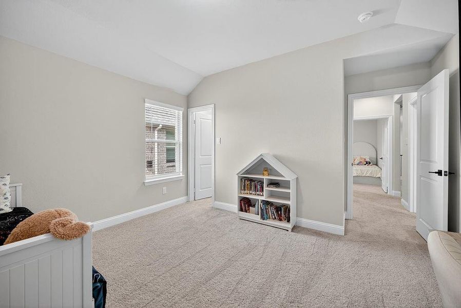 Carpeted interior space featuring vaulted ceilings, a large window with blinds, and white trim throughout
