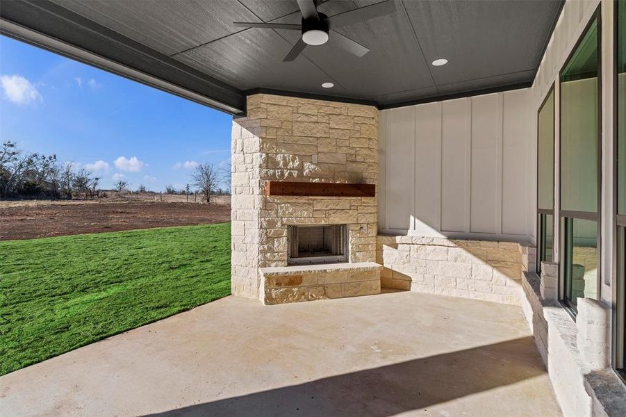 View of patio featuring ceiling fan and an outdoor stone fireplace