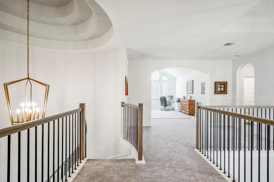 Up the stairs leads to a spacious, well-lit room with a vaulted ceiling and large windows, perfect for a home office or study.