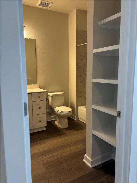 Bathroom featuring vanity, dark wood-type flooring, a textured wall, and bathtub / shower combination