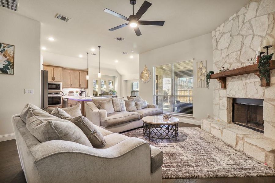 Living room with ceiling fan, dark wood-style flooring, a fireplace, and vaulted ceiling