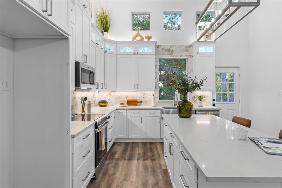 Kitchen featuring white cabinets, stainless steel appliances, light stone countertops, dark hardwood / wood-style flooring, and decorative backsplash