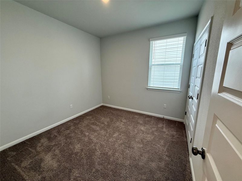 Neutral-toned interior room featuring brown carpet flooring, light gray wall paint, and white trim